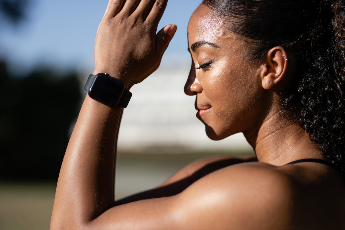 Mulher de costas, com os olhos fechados e as mãos em posição de oração, usando um smartwatch.