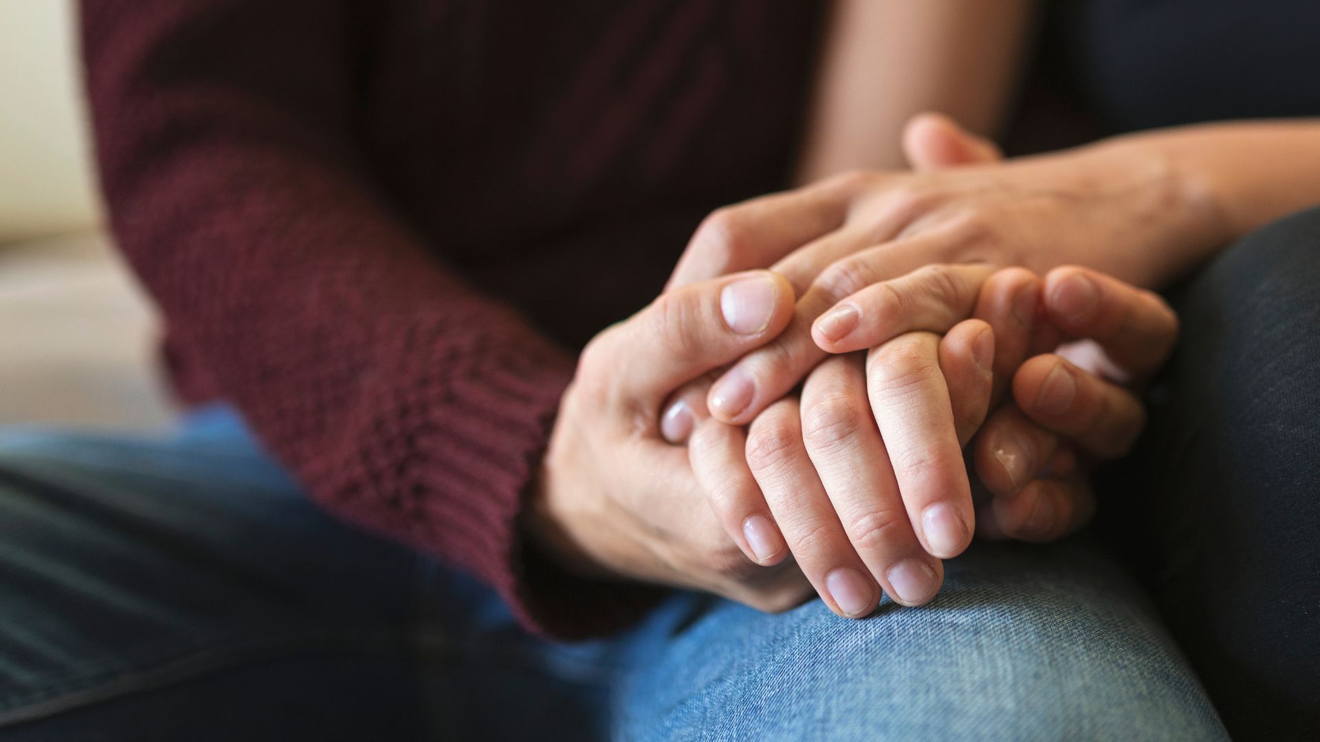 Mãos sendo seguradas em demonstração de apoio emocional.