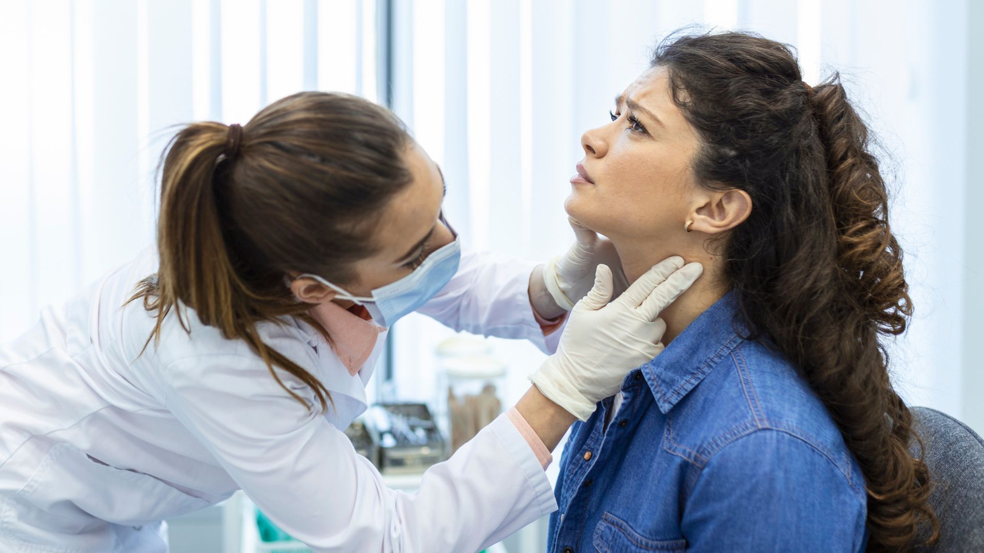 Médica examinando a tireoide de paciente.