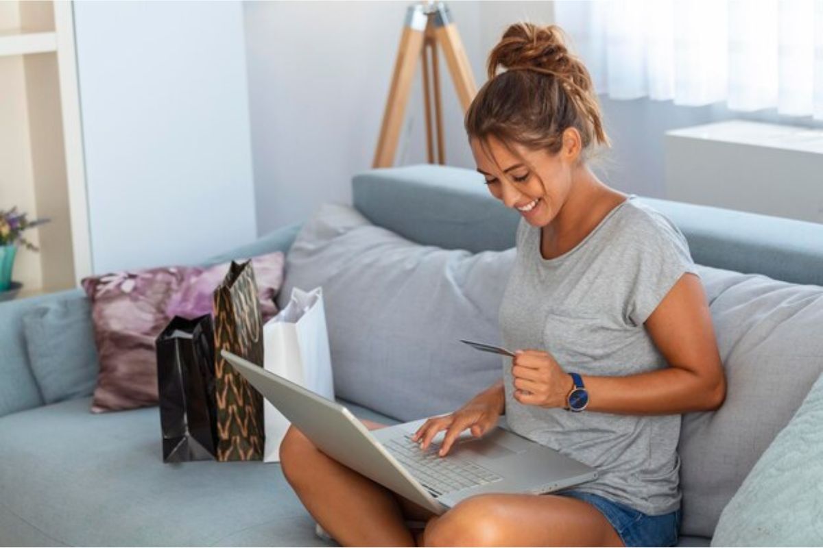 Uma mulher segura um cartão em frente ao seu notebook enquanto faz compras em Lojas Online de Eletrônicos 2024