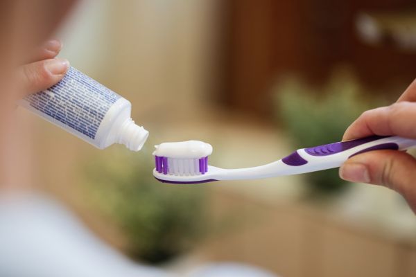 Creme dental sendo colocado na escova de dente.