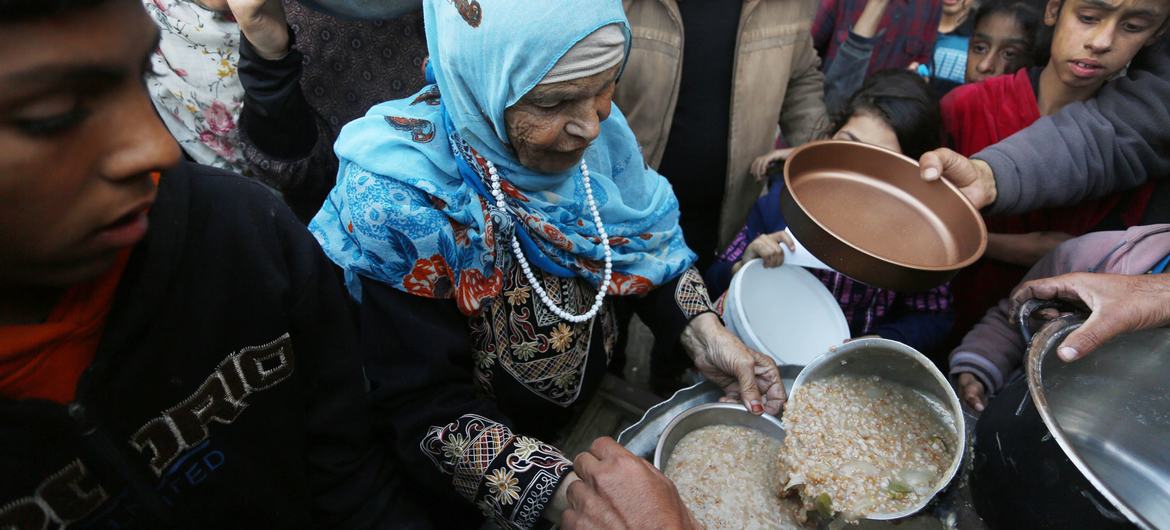 Palestinos deslocados recolhem alimentos num ponto de distribuição perto de uma escola transformada em abrigo em Gaza