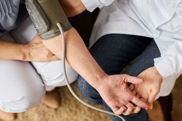 Médico e paciente sentados juntos medindo a pressão arterial.